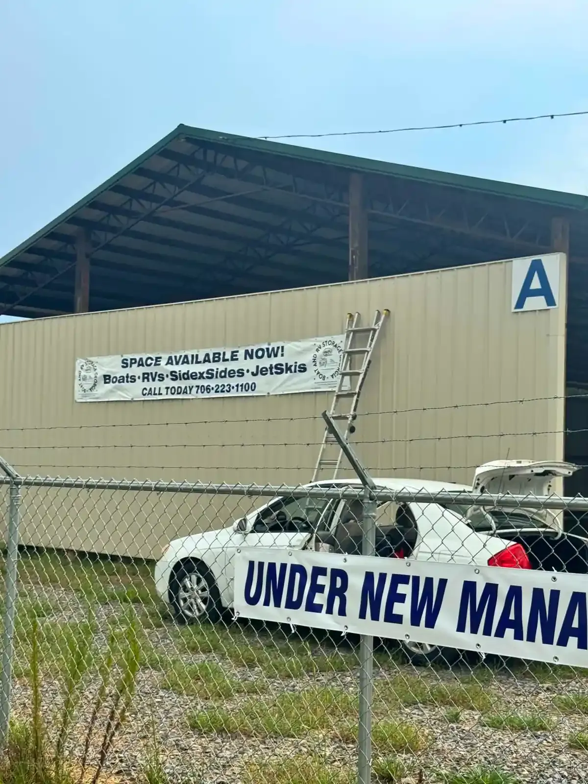 White "under new management" banner on a chain link fence